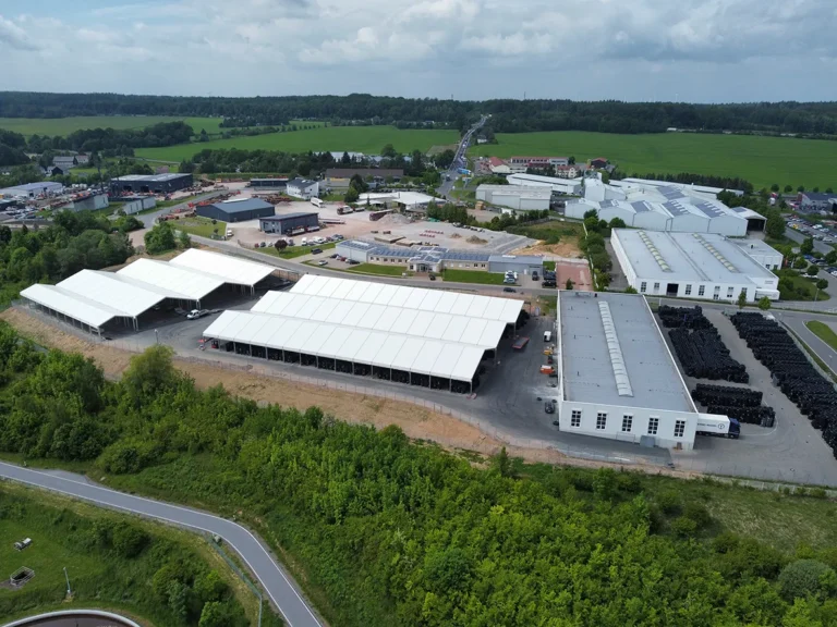 Die neuen Überdachungen (weiß im Bild) erweitern die Flächen der bestehenden beiden Standorte Ahornstraße 4 (rechts hinten, mit Büro) und Kastanienring 20 (rechts davon) auf 80.000 Lkw-Reifen Kapazität. Hinweis Fotografin: Janine Augstein, Pneuhage/Interpneu